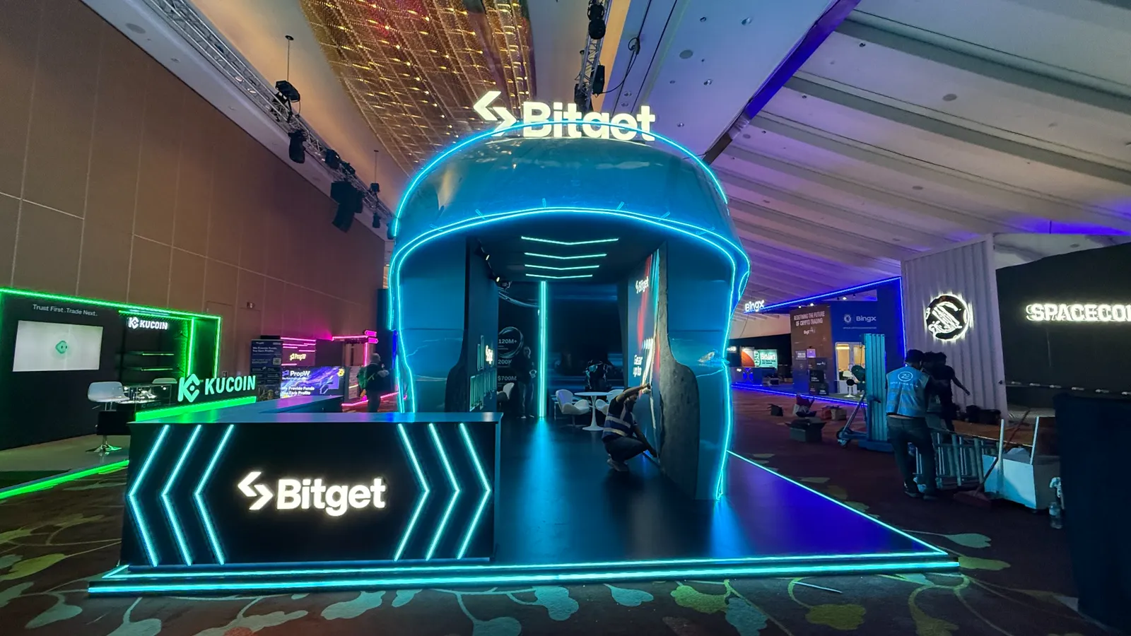 Completed Bitget exhibition booth with a sculptural blue form and illuminated edge lighting