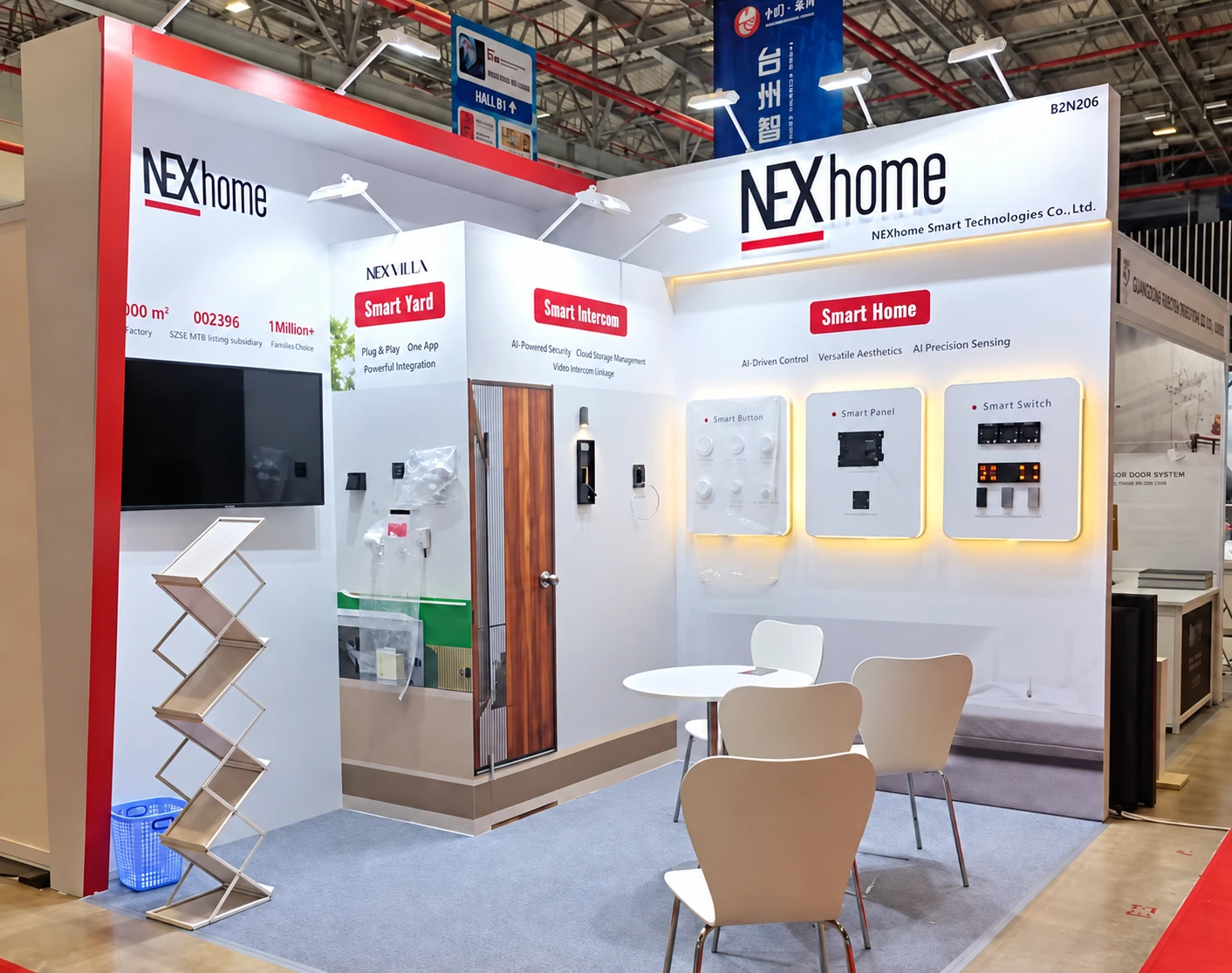 White and red NEXhome booth with smart-home panels, intercom displays and a round meeting table